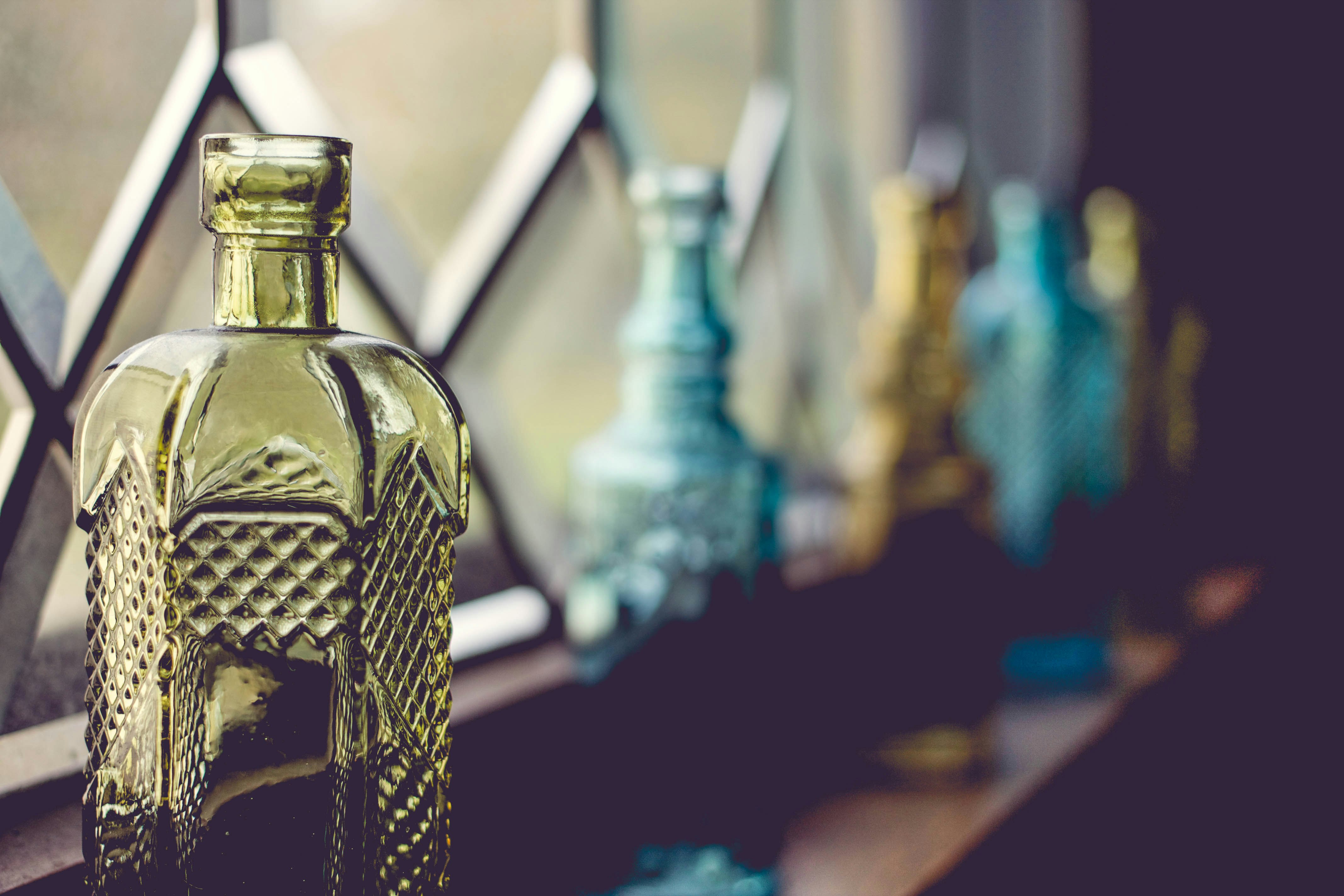 shallow focus photography of yellow glass bottle beside window